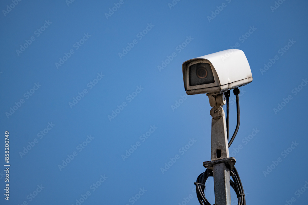White Security Camera Mounted on Pole Against Blue Sky White Security Camera Mounted on Pole Against Blue Sky