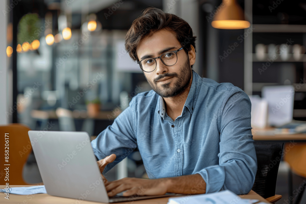 Pensive Indian Businessman with Beard and Glasses Thinking at Desk, Business Manager in Modern Office, Man in Blue Shirt Working on Laptop, Solving Problems, Portrait with Dreamy Look Pensive Indian Businessman with Beard and Glasses Thinking at Desk, Business Manager in Modern Office, Man in Blue Shirt Working on Laptop, Solving Problems, Portrait with Dreamy Look