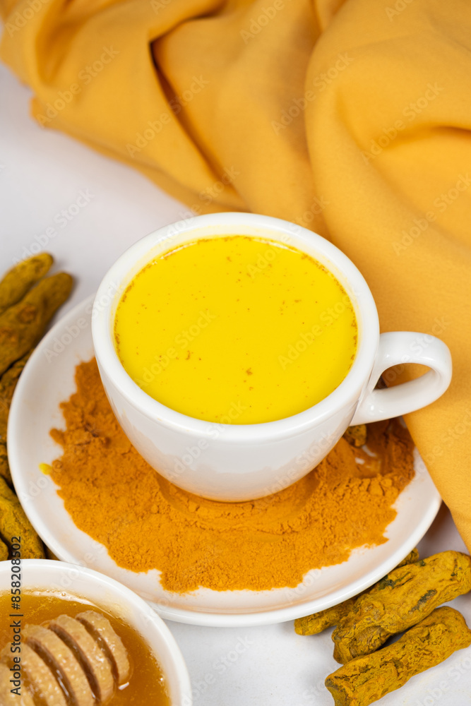 A traditional Ayurvedic drink with milk and turmeric in a white cup A traditional Ayurvedic drink with milk and turmeric in a white cup