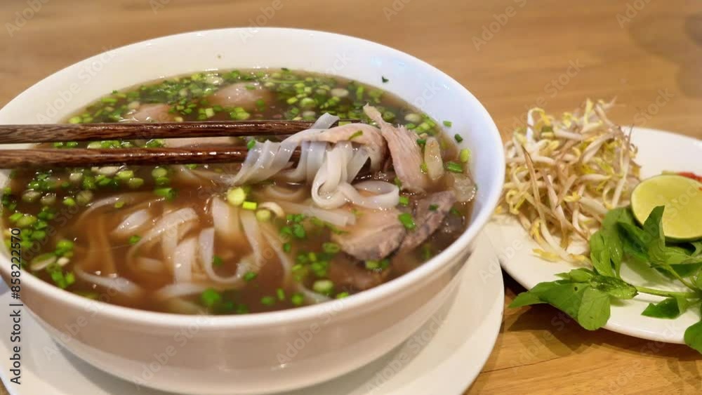a bowl of Vietnamese pho with thin rice noodles, sliced beef, fresh herbs, and lime wedge. Pho is a fragrant noodle soup perfect for any meal. a bowl of Vietnamese pho with thin rice noodles, sliced beef, fresh herbs, and lime wedge. Pho is a fragrant noodle soup perfect for any meal.