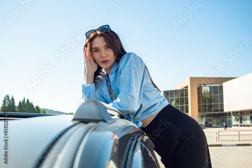 A girl stands by a car on a sunny summer day. © Zuev Ali