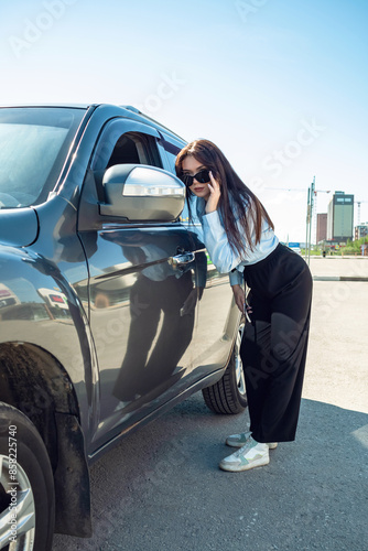 A girl with glasses looks at a car in the rearview mirror.