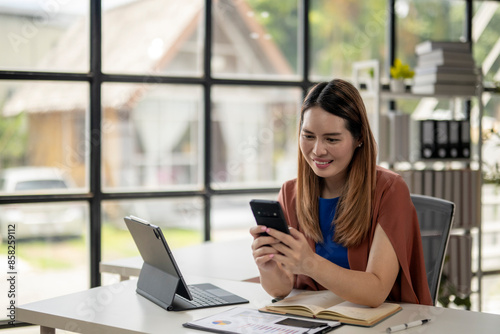 Free Download A woman is sitting at a desk with a laptop and a cell phone - GFXLoad