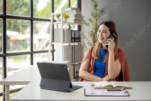 A woman is talking on her cell phone while sitting at a desk