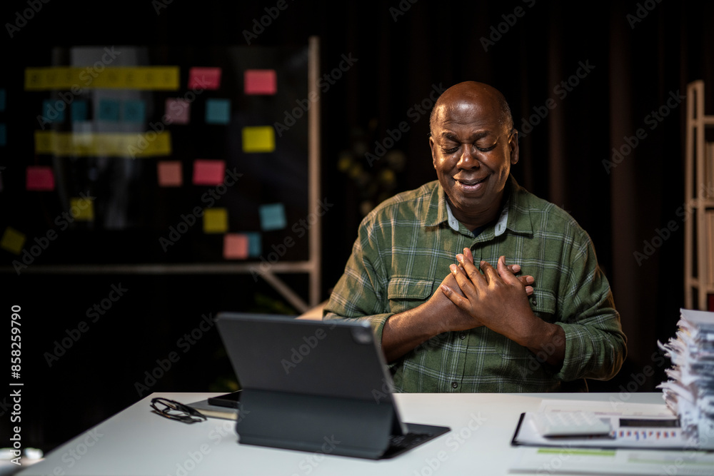 A man is sitting at a desk with a laptop and a stack of papers A man is sitting at a desk with a laptop and a stack of papers