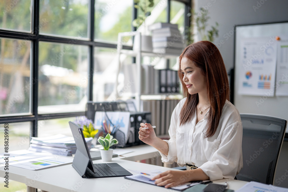 A woman is sitting at a desk with a laptop and a tablet A woman is sitting at a desk with a laptop and a tablet