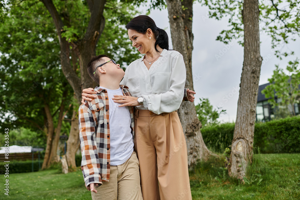 A mother and her son with Down syndrome walk together in a park, showcasing the beauty of diversity and inclusion. A mother and her son with Down syndrome walk together in a park, showcasing the beauty of diversity and inclusion.