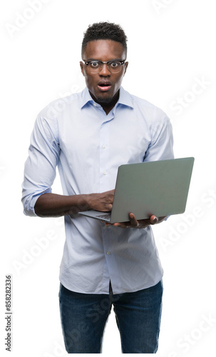 Young african american businessman using computer laptop scared in shock with a surprise face, afraid and excited with fear expression photo