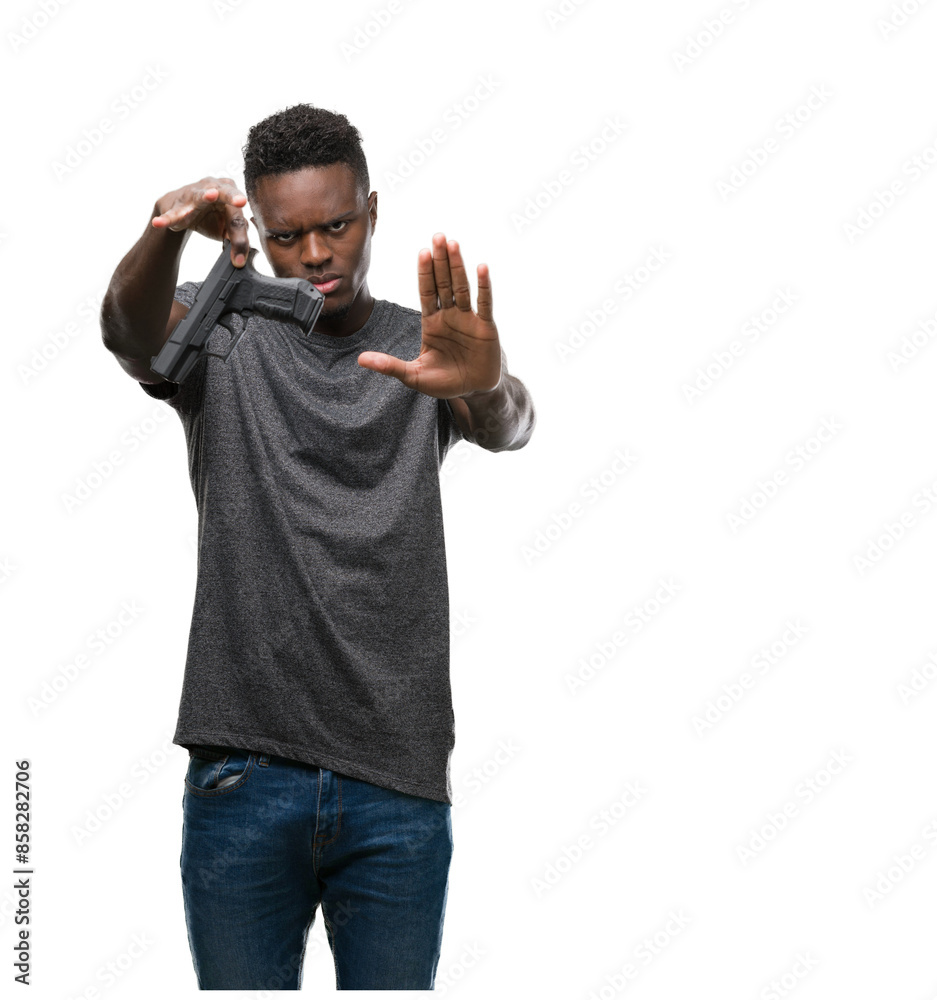 Young african american man holding a gun with open hand doing stop sign with serious and confident expression, defense gesture Young african american man holding a gun with open hand doing stop sign with serious and confident expression, defense gesture