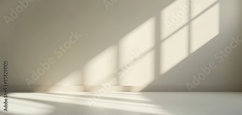 The beige color and window shadows on an empty wall in a room illustrate a minimalist style, focusing on simplicity and sophistication, suitable for various design and decor projects.