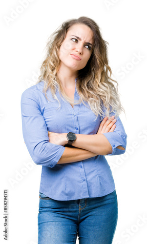 Beautiful young blonde business woman over isolated background smiling looking to the side with arms crossed convinced and confident