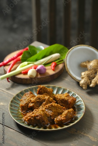 Beef rendang on rustic plate on the wooden table. This is traditional food from Indonesia. Made from beef, coconut milk, some herbs and spices photo