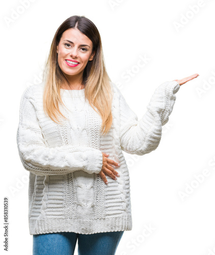 Young beautiful woman casual white sweater over isolated background smiling cheerful presenting and pointing with palm of hand looking at the camera.