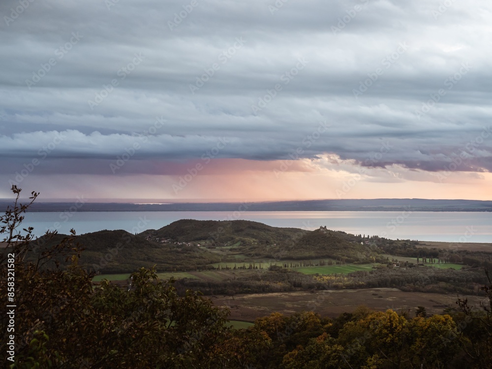 Panoramic view of the Szigliget mountain and the lake Balaton on Balatonfelvidék area of Hungary with vineyards wine region of Balaton, near sunset, pink colors, , storm coming Panoramic view of the Szigliget mountain and the lake Balaton on Balatonfelvidék area of Hungary with vineyards wine region of Balaton, near sunset, pink colors, , storm coming