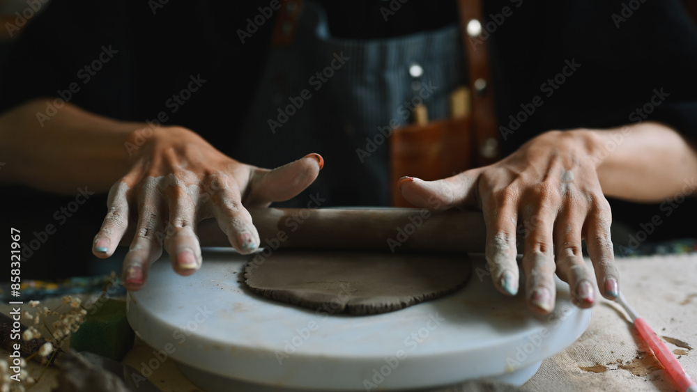 Close-up of a hand of sculptor flattening clay by roller, Crafts and DIY concept Close-up of a hand of sculptor flattening clay by roller, Crafts and DIY concept