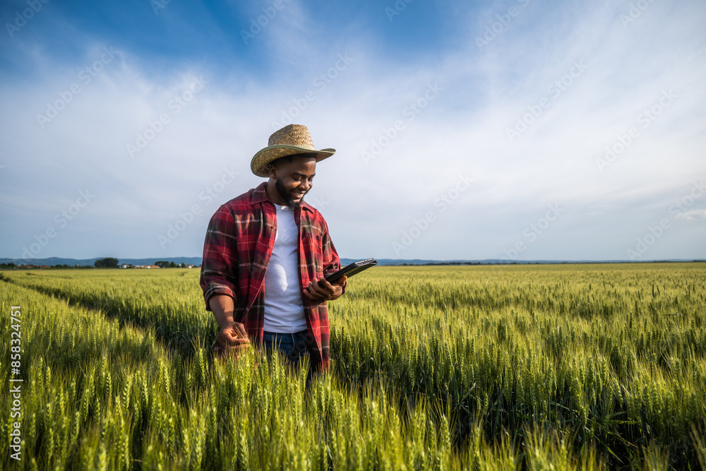 Young farmer using digital tablet while standing in his growing wheat field. Young farmer using digital tablet while standing in his growing wheat field.