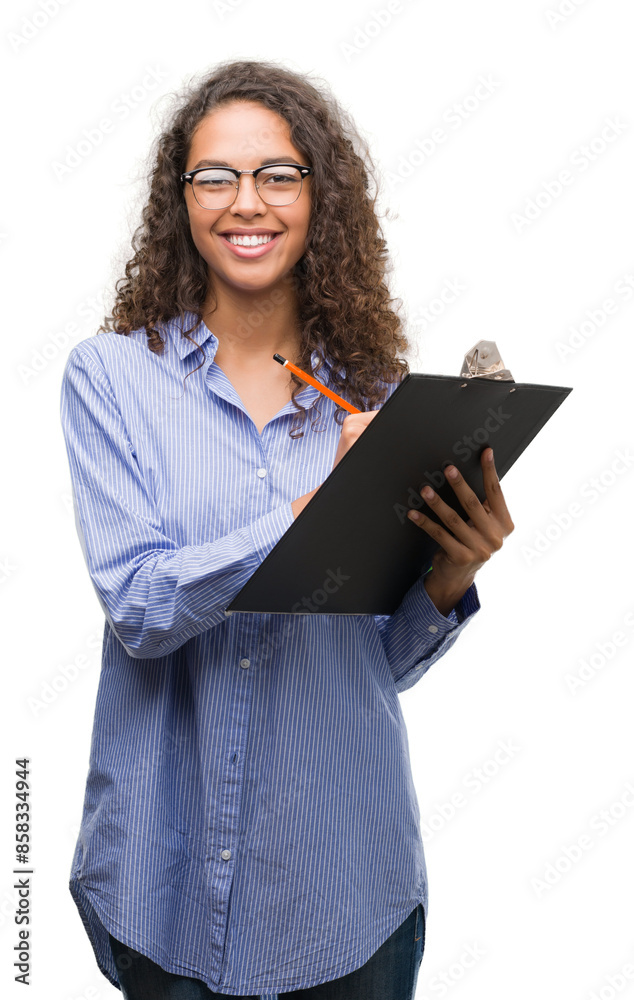 Young hispanic business woman holding clipboard with a happy face standing and smiling with a confident smile showing teeth