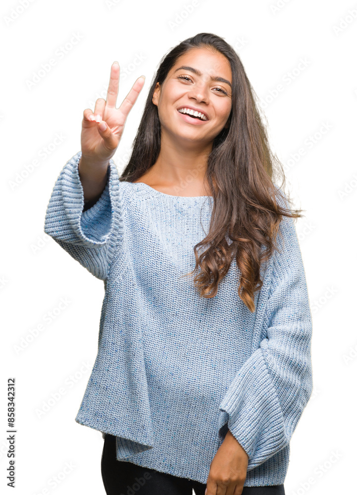 Young beautiful arab woman wearing winter sweater over isolated background smiling with happy face winking at the camera doing victory sign. Number two. Young beautiful arab woman wearing winter sweater over isolated background smiling with happy face winking at the camera doing victory sign. Number two.