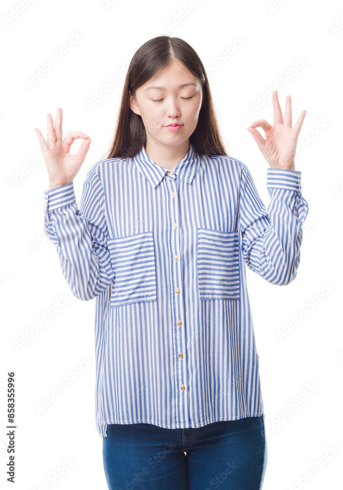 Young Chinese woman over isolated background relax and smiling with eyes closed doing meditation gesture with fingers. Yoga concept. Young Chinese woman over isolated background relax and smiling with eyes closed doing meditation gesture with fingers. Yoga concept.