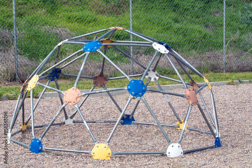 Empty geodesic dome style jungle gym with colorful six slotted connectors on pea gravel playground