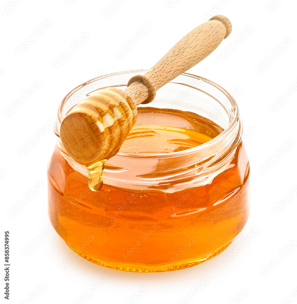 Glass jar full of honey and wooden dipper on white background Glass jar full of honey and wooden dipper on white background