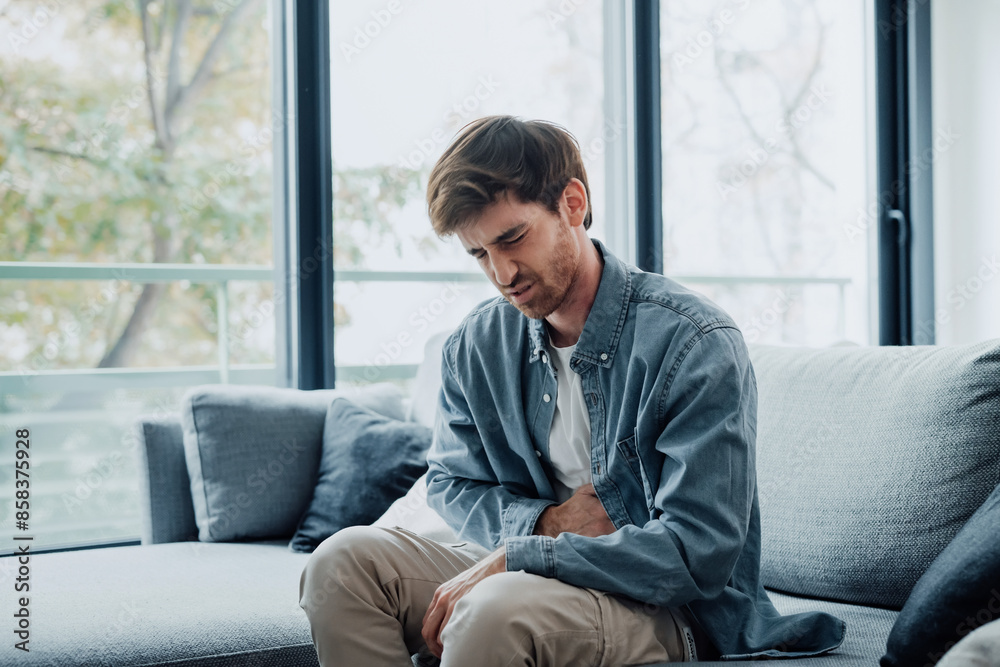 Sick young man in pain holding belly stomach feeling hurt abdomen ache gastritis pancreatitis symptoms or diarrhea, upset adult suffering from indigestion flatulence abdominal problem concept. Sick young man in pain holding belly stomach feeling hurt abdomen ache gastritis pancreatitis symptoms or diarrhea, upset adult suffering from indigestion flatulence abdominal problem concept.
