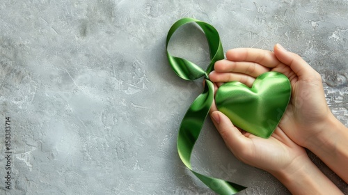 Template featuring a hand holding a green ribbon with a heart, isolated on a grey background, promoting organ donation photo
