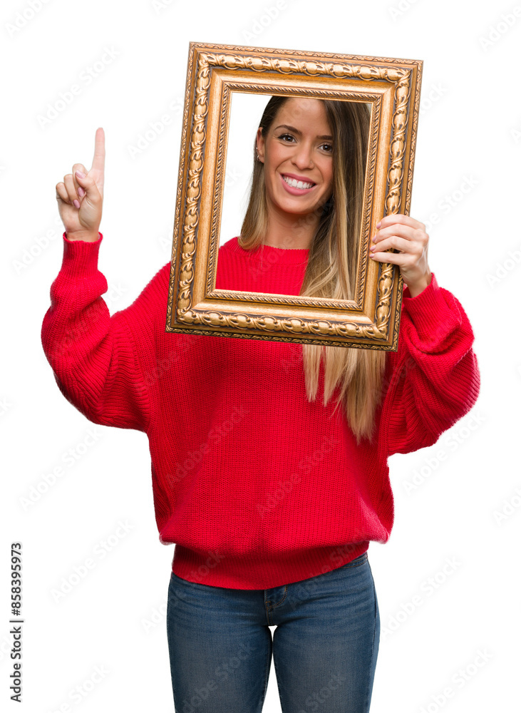 Fototapeta premium Beautiful young woman holding vintage frame surprised with an idea or question pointing finger with happy face, number one