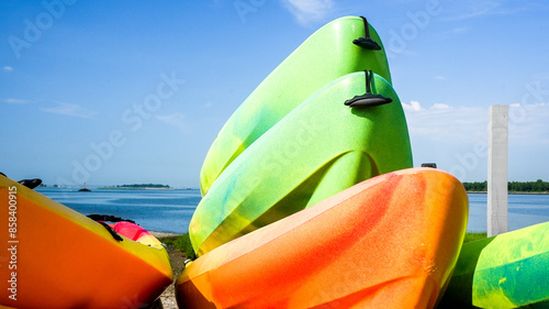 Colorful kayaks stacked on shore at a beach on a Summer sunny day