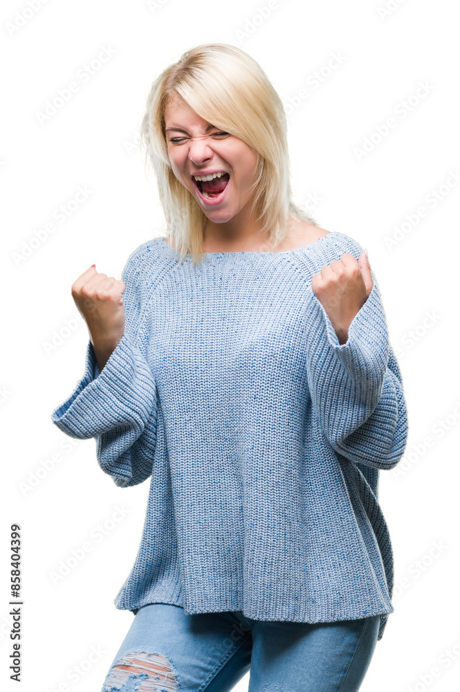 Young beautiful blonde woman wearing winter sweater over isolated background very happy and excited doing winner gesture with arms raised, smiling and screaming for success. Celebration concept.