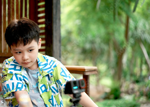 Child boy using camera in summer nature. Photographer, fall season and leisure concept. photo