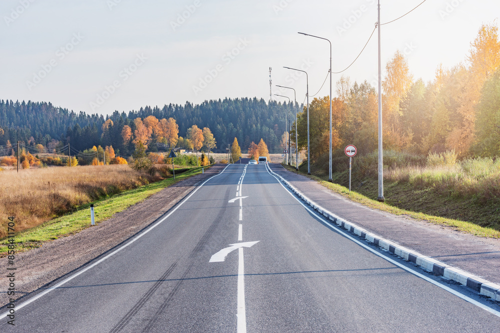 Fototapeta premium Road across countryside at autumn sunset.