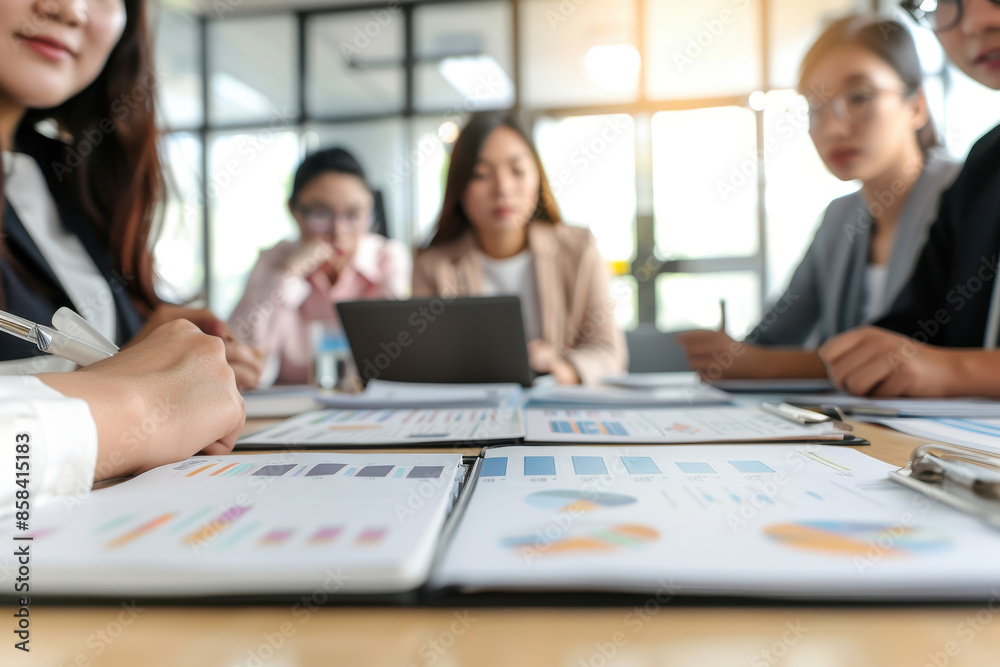 Business meeting with colleagues discussing financial reports and charts. Focus on documents and teamwork in a modern office setting. Business meeting with colleagues discussing financial reports and charts. Focus on documents and teamwork in a modern office setting.