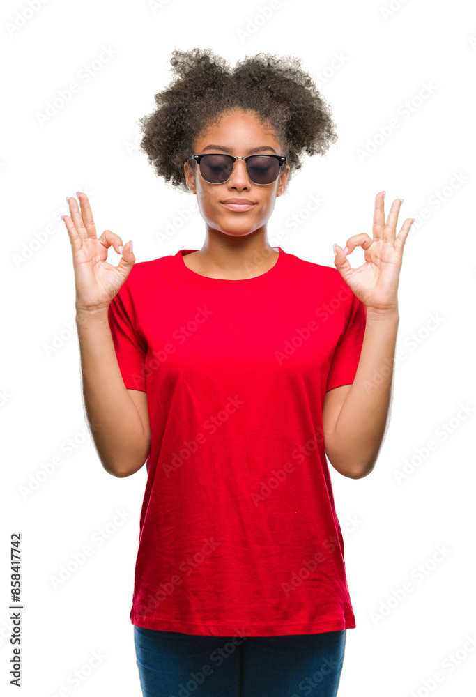 Young afro american woman wearing sunglasses over isolated background relax and smiling with eyes closed doing meditation gesture with fingers. Yoga concept. Young afro american woman wearing sunglasses over isolated background relax and smiling with eyes closed doing meditation gesture with fingers. Yoga concept.