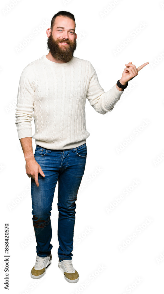 Young hipster man wearing winter sweater with a big smile on face, pointing with hand and finger to the side looking at the camera. Young hipster man wearing winter sweater with a big smile on face, pointing with hand and finger to the side looking at the camera.