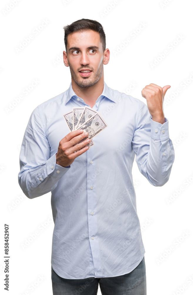 Handsome young man holding money pointing with hand and finger up with happy face smiling Handsome young man holding money pointing with hand and finger up with happy face smiling