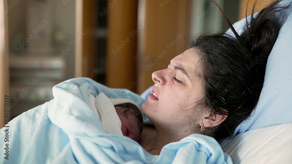 New mother in discomfort after post-partum trauma at hospital clinic holding newborn on chest. woman in pain after childbirth, real life authentic emotion of human struggle New mother in discomfort after post-partum trauma at hospital clinic holding newborn on chest. woman in pain after childbirth, real life authentic emotion of human struggle