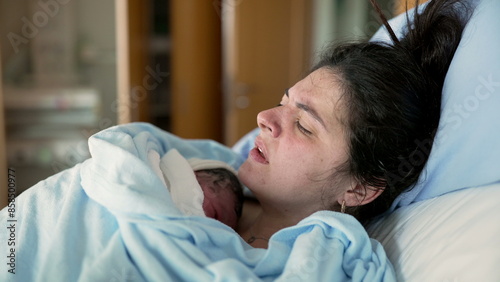 Obraz na plátně New mother in discomfort after post-partum trauma at hospital clinic holding newborn on chest