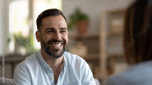 Therapist Focus on a male therapist White 40s listening to a patient with a therapy room background, empty space left for text Happy face and smile Look at camera