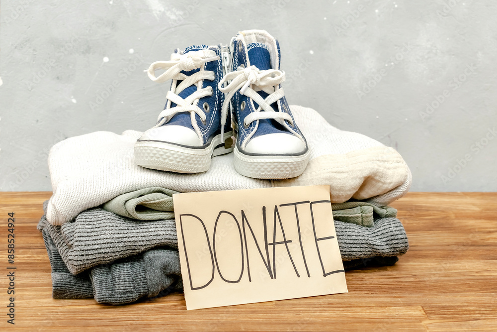 Stack of old baby children clothes,sneakers sorted into Donate categories.Donation,volunteering help,humanitarian aid.charity on gray background.Recycle clothing,eco cotton. Stack of old baby children clothes,sneakers sorted into Donate categories.Donation,volunteering help,humanitarian aid.charity on gray background.Recycle clothing,eco cotton.