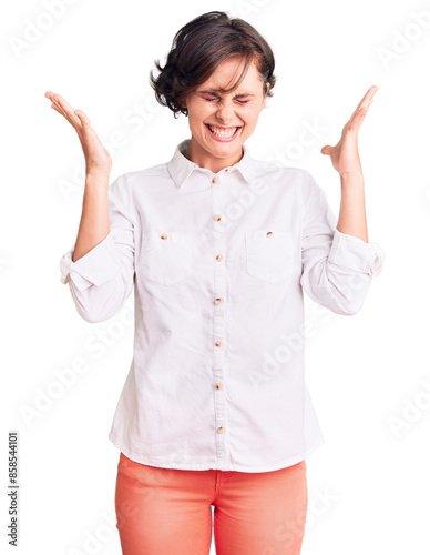 Beautiful young woman with short hair wearing elegant white shirt celebrating mad and crazy for success with arms raised and closed eyes screaming excited. winner concept