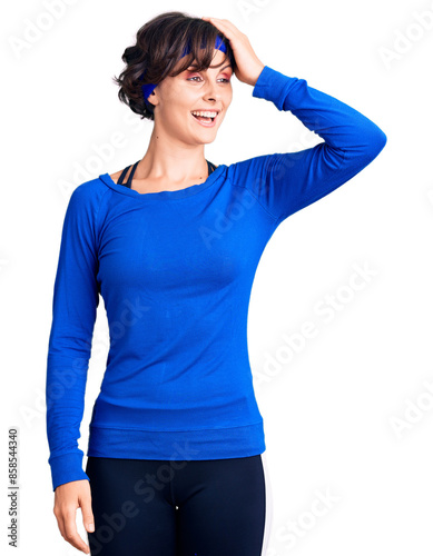 Beautiful young woman with short hair wearing training workout clothes smiling confident touching hair with hand up gesture, posing attractive and fashionable