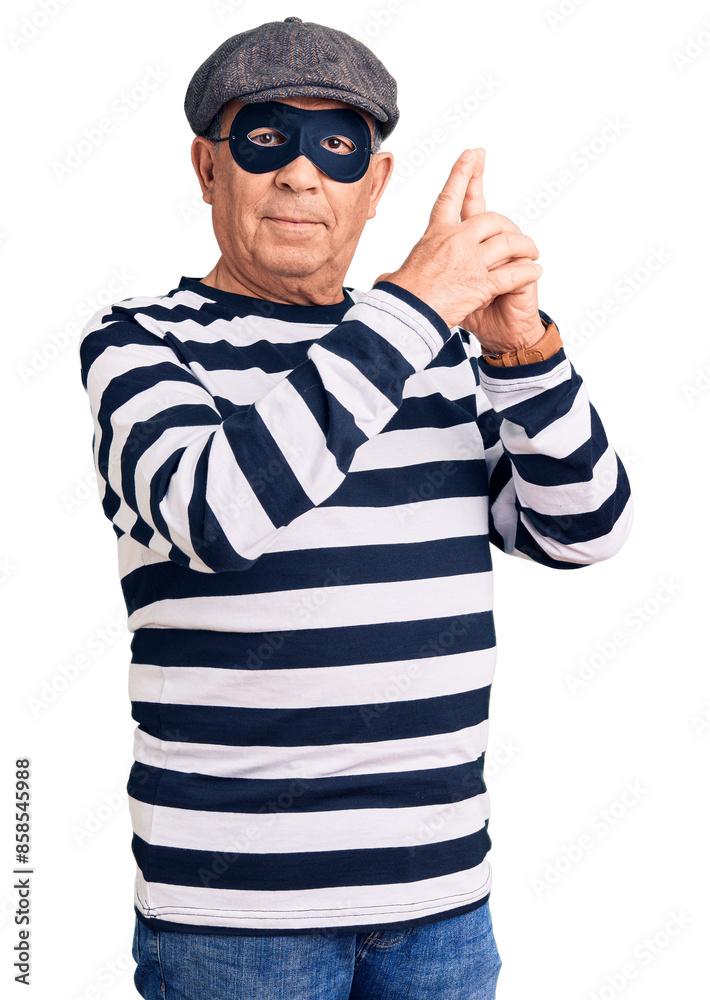 Senior handsome man wearing burglar mask and t-shirt holding symbolic gun with hand gesture, playing killing shooting weapons, angry face Senior handsome man wearing burglar mask and t-shirt holding symbolic gun with hand gesture, playing killing shooting weapons, angry face