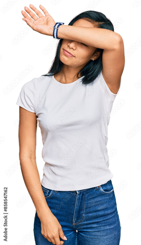Beautiful hispanic woman wearing casual white tshirt covering eyes with arm, looking serious and sad. sightless, hiding and rejection concept Beautiful hispanic woman wearing casual white tshirt covering eyes with arm, looking serious and sad. sightless, hiding and rejection concept