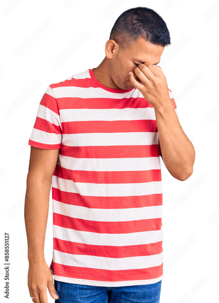 Young handsome latin man wearing casual clothes tired rubbing nose and eyes feeling fatigue and headache. stress and frustration concept. Young handsome latin man wearing casual clothes tired rubbing nose and eyes feeling fatigue and headache. stress and frustration concept.