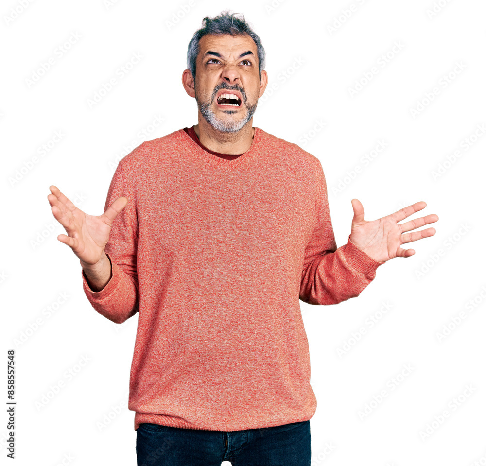Middle age hispanic with grey hair wearing casual sweater crazy and mad shouting and yelling with aggressive expression and arms raised. frustration concept. Middle age hispanic with grey hair wearing casual sweater crazy and mad shouting and yelling with aggressive expression and arms raised. frustration concept.