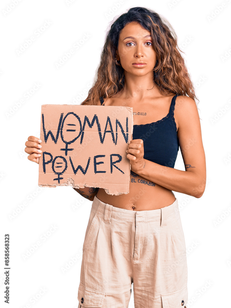 Young hispanic woman with tattoo holding woman power banner thinking attitude and sober expression looking self confident Young hispanic woman with tattoo holding woman power banner thinking attitude and sober expression looking self confident