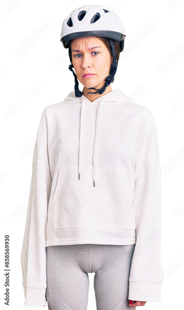 Beautiful brunette young woman wearing bike helmet and sporty clothes relaxed with serious expression on face. simple and natural looking at the camera. Beautiful brunette young woman wearing bike helmet and sporty clothes relaxed with serious expression on face. simple and natural looking at the camera.