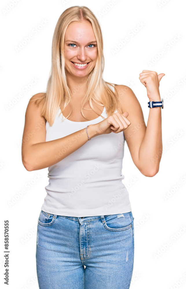 Obraz premium Young blonde girl wearing casual style with sleeveless shirt pointing to the back behind with hand and thumbs up, smiling confident