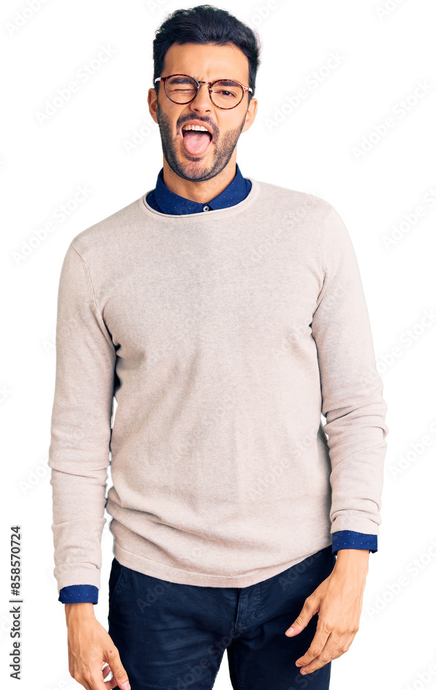 Young handsome hispanic man wearing elegant clothes and glasses winking looking at the camera with sexy expression, cheerful and happy face. Young handsome hispanic man wearing elegant clothes and glasses winking looking at the camera with sexy expression, cheerful and happy face.